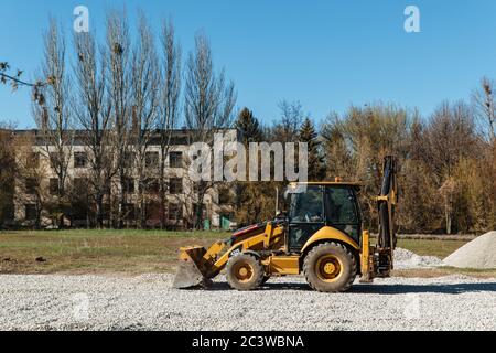 Dneprorudnoe/Ucraina - Aprile 08 2020: Un trattore versa la ghiaia dalla benna Foto Stock