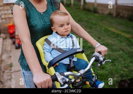 Una madre caucasica guida un bel bambino in bicicletta Foto Stock