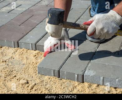 Installazione di lastre di pavimentazione su base sabbiosa Foto Stock