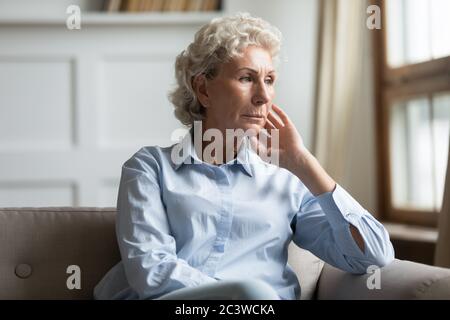 Donna anziana preoccupata perduta in pensieri tristi seduti sul divano Foto Stock