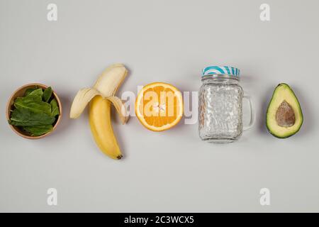 banana frutta, avocado, arancia, spinaci su sfondo grigio. ingredienti frullati verdi. cibo sano eco-friendly concetto. Foto Stock