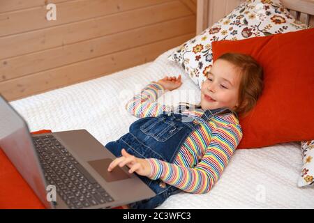 Una bambina guarda il computer con diverse emozioni. Ragazza gioca su un computer Foto Stock