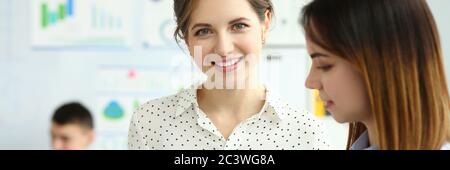 Bella donna sorridente che guarda in macchina fotografica durante il processo di lavoro in ufficio Foto Stock