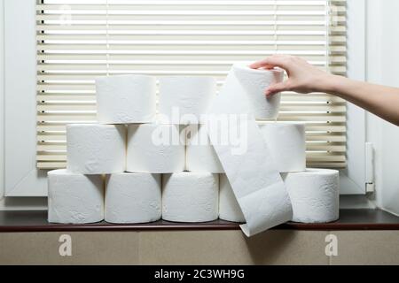 Una mano prende un rotolo di carta igienica dal davanzale nella toilette Foto Stock