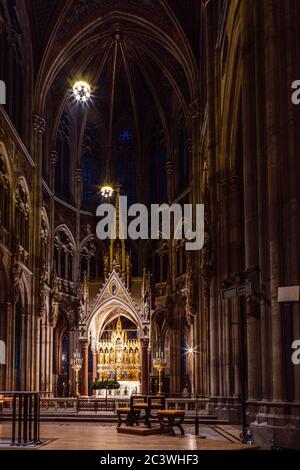 Vista notturna interna con altare maggiore, coro, della Chiesa votiva neo-gotica (Votivkirche), Vienna, Austria. Foto Stock
