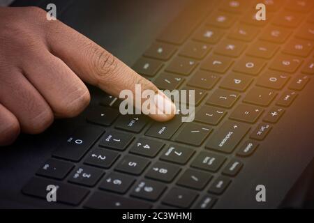 Il dito indice preme il tasto invio sulla tastiera del portatile Foto Stock
