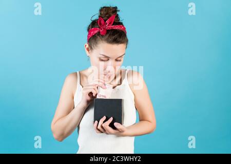 Una giovane donna guarda in una banca piggy, dove mette o prende dieci euro Foto Stock