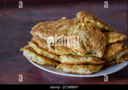 Una pila di deliziosi brizoli fritti su un piatto. Brisoli di carne appena cotta sul tavolo da cucina. Piatti di carne. Primo piano. Foto Stock