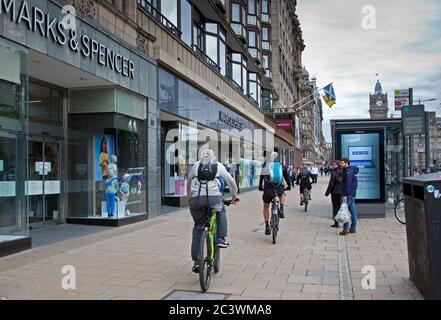 Edimburgo, Scozia, Regno Unito. 22 giugno 2020. Sebbene le strade e i marciapiedi di Edimburgo siano ancora relativamente tranquilli per il traffico motorizzato a causa dei ciclisti Coronavirus Covid-19 continuano a pedalare lungo i marciapiedi per il loro viaggio, spesso causando pedoni a deglutire o fermarsi per evitare collisioni. Nella foto: Una fila di ciclisti in Princes Street che costringono due persone ad attendere fino al loro passaggio. Foto Stock