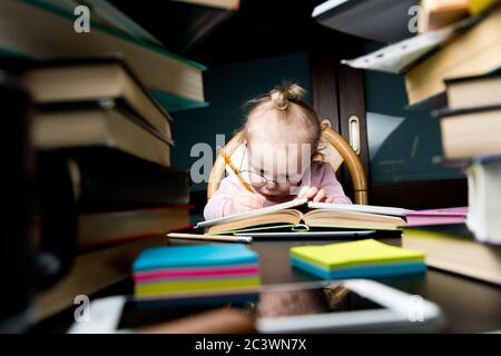 Un bambino in grandi vetri scrive dolorosamente qualcosa in un notebook Foto Stock