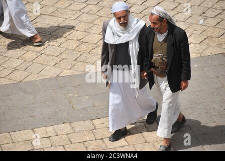 Sanaa, Yemen - 6 marzo 2010: Due uomini a piedi non identificati mano in mano chiacchierano su una strada nella città vecchia di Sanaa Foto Stock