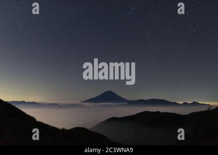 Monte Fuji su un mare di nuvole sotto un cielo stellato di notte Foto Stock