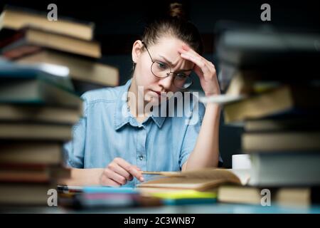 Lo studente guarda con cura i materiali di studio, ma continua a studiare in ritardo Foto Stock