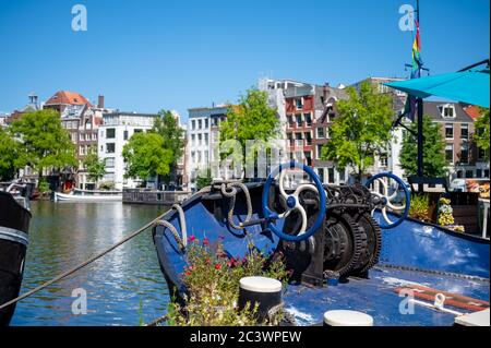 Barche ed edifici sulle rive del fiume Amstel ad Amsterdam, Paesi Bassi Foto Stock