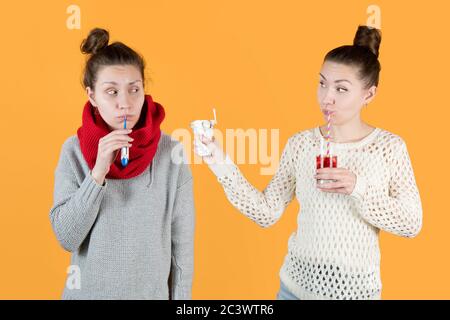 La ragazza si offre di aiutare se stessa e tiene fuori le medicine, bevendo succo fresco Foto Stock