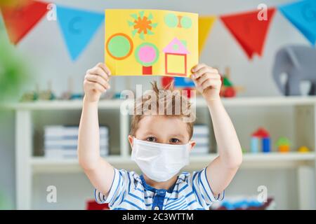 Adorabile ragazzino in asilo con maschera a causa di pandemia di coronavirus Foto Stock