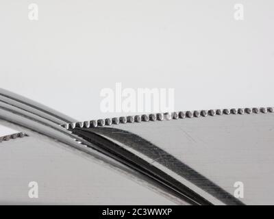 Bordo dentellato di un coltello da tavolo in un sommario di primo piano dei rebbi della forca Foto Stock
