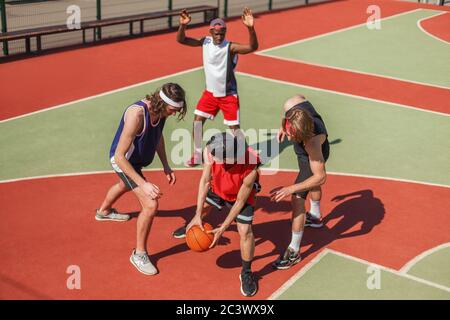 Giovani sportivi multietnici che giocano a una partita di pallacanestro nel parco giochi all'aperto Foto Stock