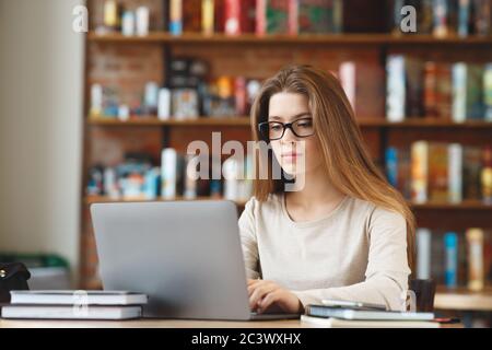 Giovane ragazza che scrive blog, chattando in linea, lavorando sul laptop Foto Stock