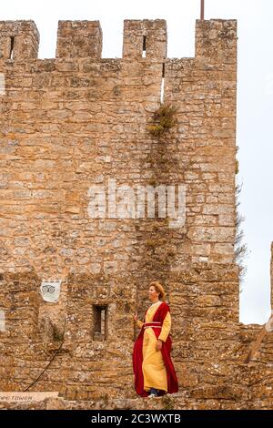 Donna vestita in costume medievale contro le mura del castello durante la festa medievale di Óbidos Portogallo Foto Stock