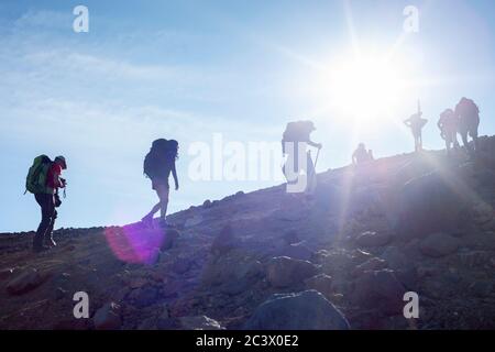 La gente che saliva sul cratere Rosso con i raggi del sole che splende sul Tongariro Alpine Crossing in Nuova Zelanda. Foto Stock