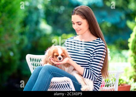 Scatto di donna attraente che si rilassa con il suo cucciolo carino nel giardino a casa. Foto Stock