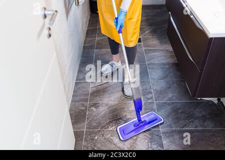 Cameriera fare chores a casa tenendo il bastone di pulizia. Concetto di prevenzione del coronavirus. Foto Stock