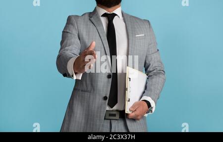Primo piano vista di uomo d'affari che si estende la mano per scuotere su sfondo blu Foto Stock
