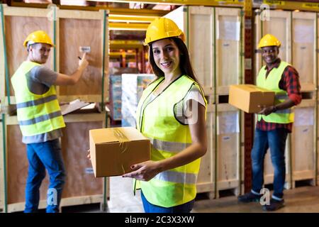 Ritratto di caucasica bianco donna magazzino lavoratore tenere scatola pacchi con il suo collega lavorando su stock in magazzino ambiente centro di distribuzione Foto Stock