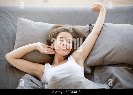 Bella ragazza giovane che si allunga a letto dopo il risveglio al mattino, vista dall'alto Foto Stock