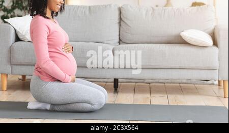 Foto di profilo ritagliata di una donna incinta che si esercita a casa Foto Stock