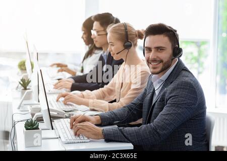 Team di agenti del servizio clienti con cuffie che lavorano su computer in ufficio, spazio vuoto Foto Stock