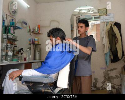 SANAA, YEMEN - 6 MARZO 2010: Uomini sconosciuti mostrati nel barbiere di strada nella vecchia Sanaa. Abitata per più di 2.500 anni ad un'altitudine di 2.200 m, Foto Stock