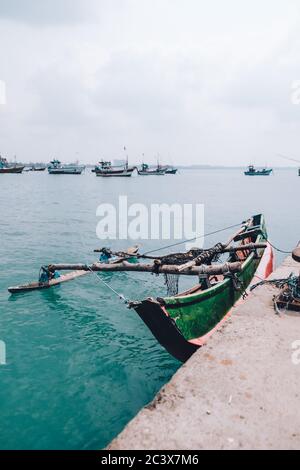 Fuga di pesca tour su una bella isola Sri Lanka. Imbarcazione singola dipinta legata alla riva. Paesaggio triste e solitario. Vista dal dock vicino Foto Stock