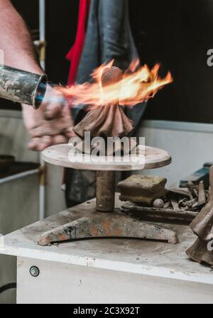 Cordoba / Spagna - 2019: Artigiano locale che brucia figurine in ceramica terrana con fiamma aperta in un negozio di souvenir. Fare la statua in un negozio. Creta che crafting Foto Stock