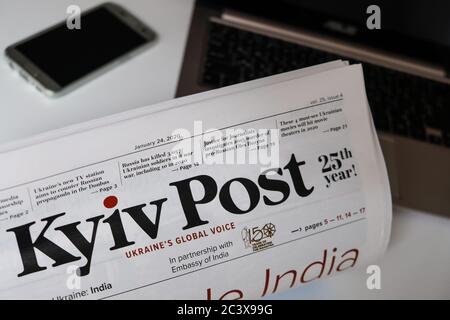 Lviv / Ucraina - Marzo 2020: Leggere la prima pagina del giornale ucraino Kiev Post a casa. Studiare contenuti didattici stampati, lavorare da casa Foto Stock