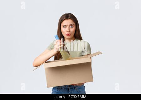 Consegna online a domicilio, ordini via internet e concetto di acquisto di generi alimentari. Donna confuso open box con ordine di alimentari su Internet, bottiglia di vino da take-out e. Foto Stock