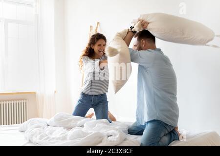 I cuscini di una giovane coppia contentano e ridono a letto. Foto Stock