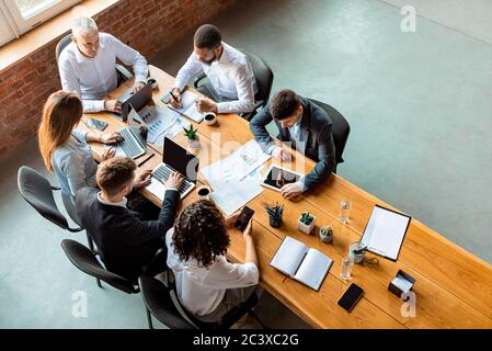 Team aziendale multirazziale che lavora seduto al tavolo in ufficio, ad alta angolazione Foto Stock