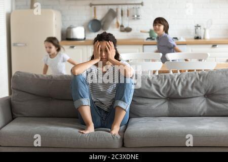 Bambini iperattivi stanchi e in corsa vicino alla madre sconvolta. Foto Stock