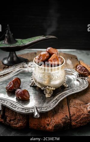 Antico vaso di datteri su un grande vassoio d'argento composizione festosa di Ramadan Kareem. Foto Stock