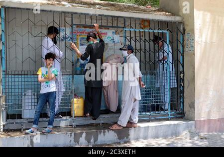 I cittadini riempiono le loro lattine d'acqua dal rubinetto pubblico, poiché si trovano a dover affrontare la carenza di acqua potabile nella loro zona, a Quetta, lunedì 22 giugno 2020. Foto Stock