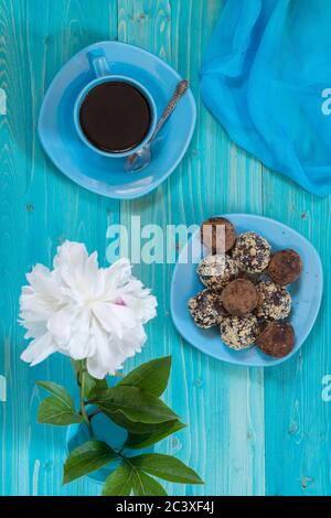 Una porzione di palle energetiche fatte in casa e una tazza di caffè nero su un tavolo di legno blu. Dessert gustoso e sano. Stile di vita. La vista dall'alto Foto Stock