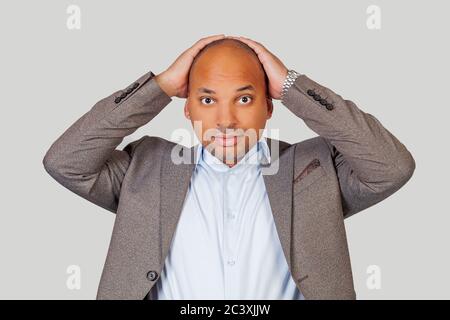 L'americano africano attraente ragazzo che tiene la testa con le mani che hanno un'espressione scomoda guardando il suo migliore amico che fa qualcosa di stupido in pubblico. Foto Stock