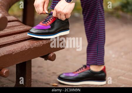 Immagine ritagliata di imprenditore legatura di sua scarpa sul banco di lavoro Foto Stock