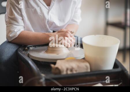 La fabbricazione di ceramica. Donna preparare argilla per il lavoro su ruota in ceramica. Vista ravvicinata delle mani. Foto Stock