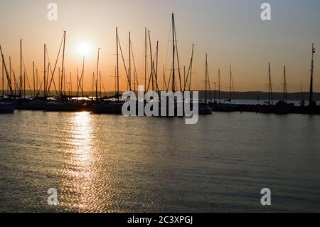 Incredibile tramonto sul lago Balaton Ungheria con barche a vela nel porto. Il sole sta riflettendo sull'acqua. Foto Stock