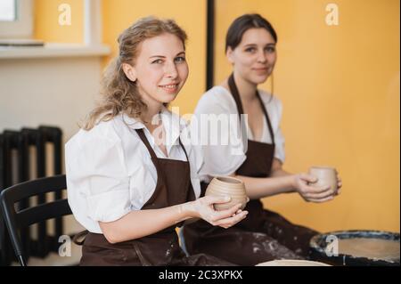 Le vaschette femmina finì di fare un vaso di argilla rimuoverlo dalla ruota del vasaio. Creazione vaso di argilla bianca. Produzione di prodotti ceramici da argilla bianca Foto Stock