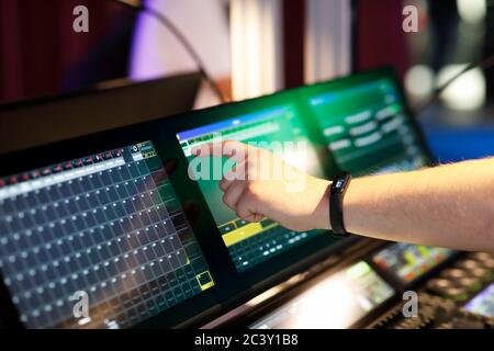 Progettista di illuminazione che lavora con la console di controllo dell'illuminazione della scena utilizzando il touchscreen. Messa a fuoco selettiva. Foto Stock