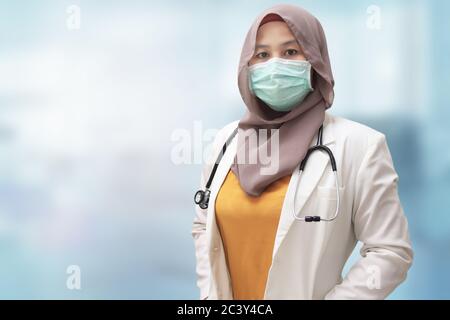Donna musulmana che indossa hijab e tuta, in piedi con maschera protettiva viso, pronto a combattere coronavirus covid19 pandemia globale Foto Stock